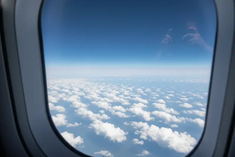 Detailaufnahme gepackter Reiseutensilien: Sonnenbrille, Reisepass und Koffer auf dem Bett vor dem Abflug