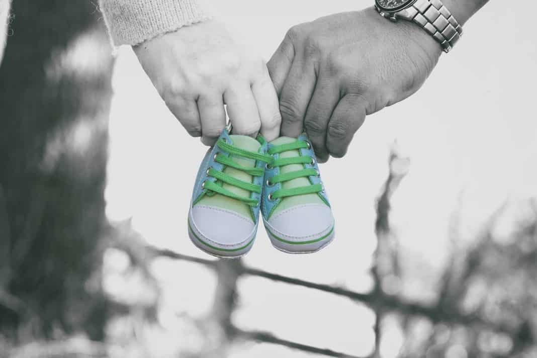 Eltern halten Babyschuhe in den Händen